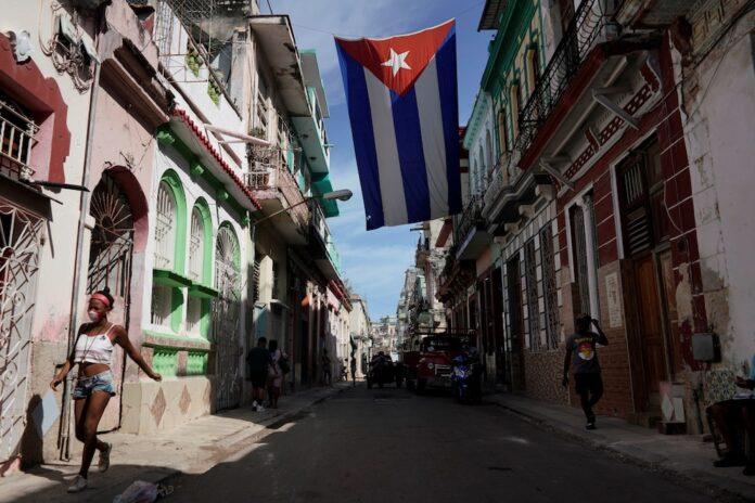 People walk under a Cuban flag hanging in the center of Havana, Cuba, October 8, 2021. REUTERS/Alexandre Meneghini